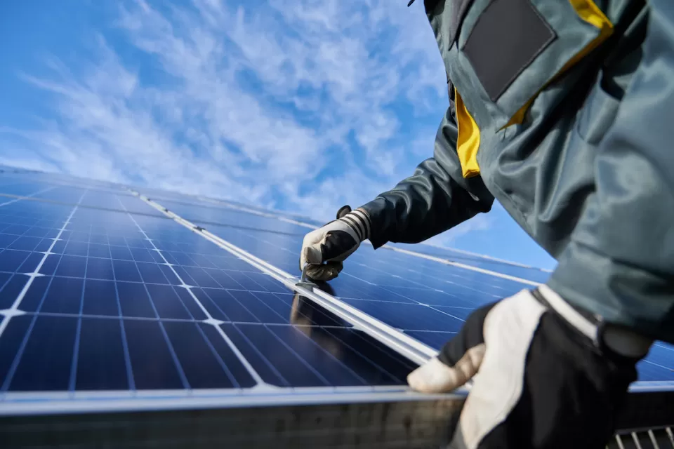 Close-up of technician wearing gloves installing photovoltaic solar panel.